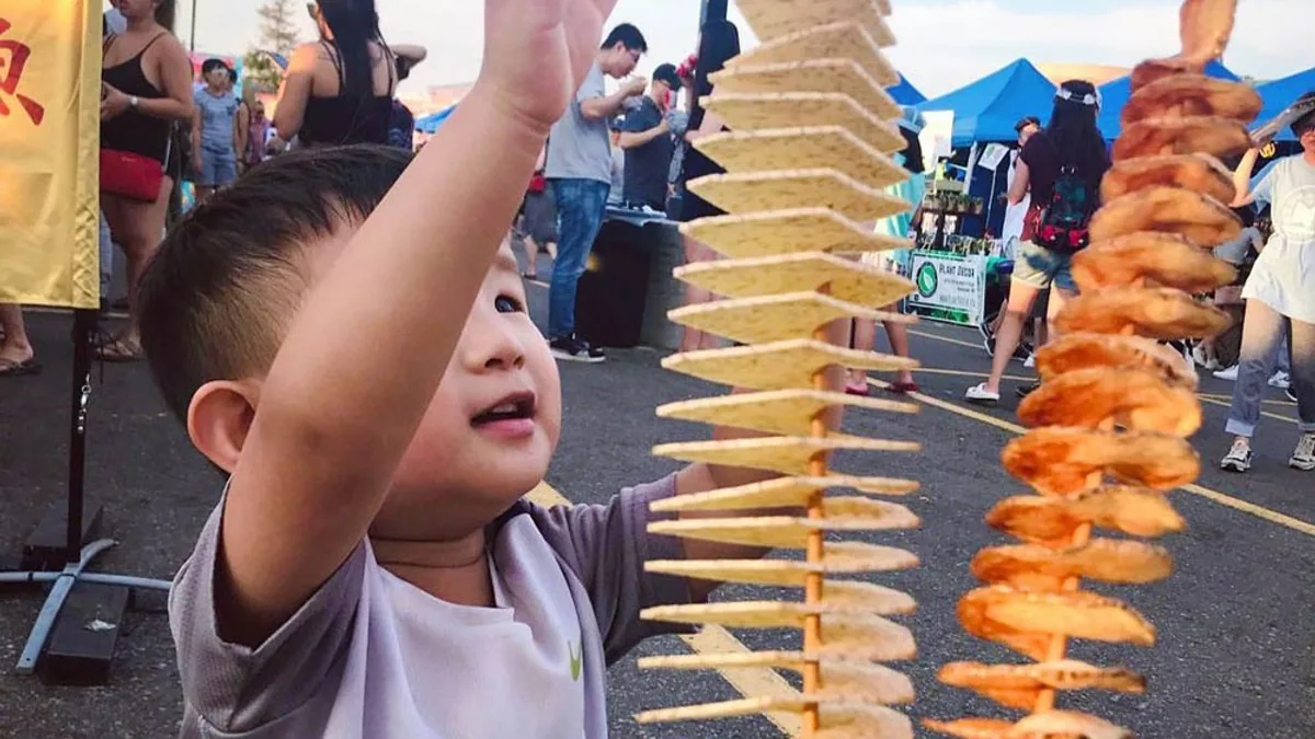 A visitor enjoying a potato skewer at Ottawa Asian Fest